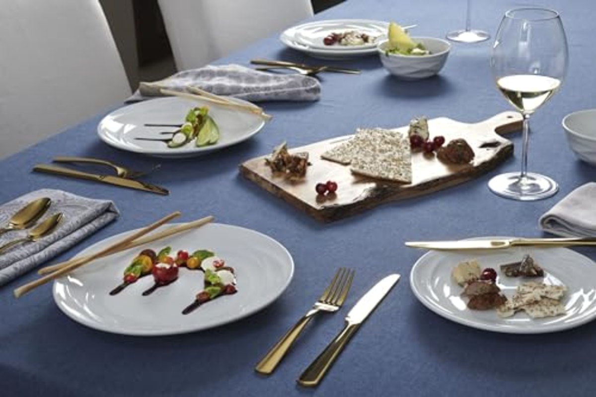 A long table under a deep blue cloth, gold-toned flatware set at each place beside a sharing board