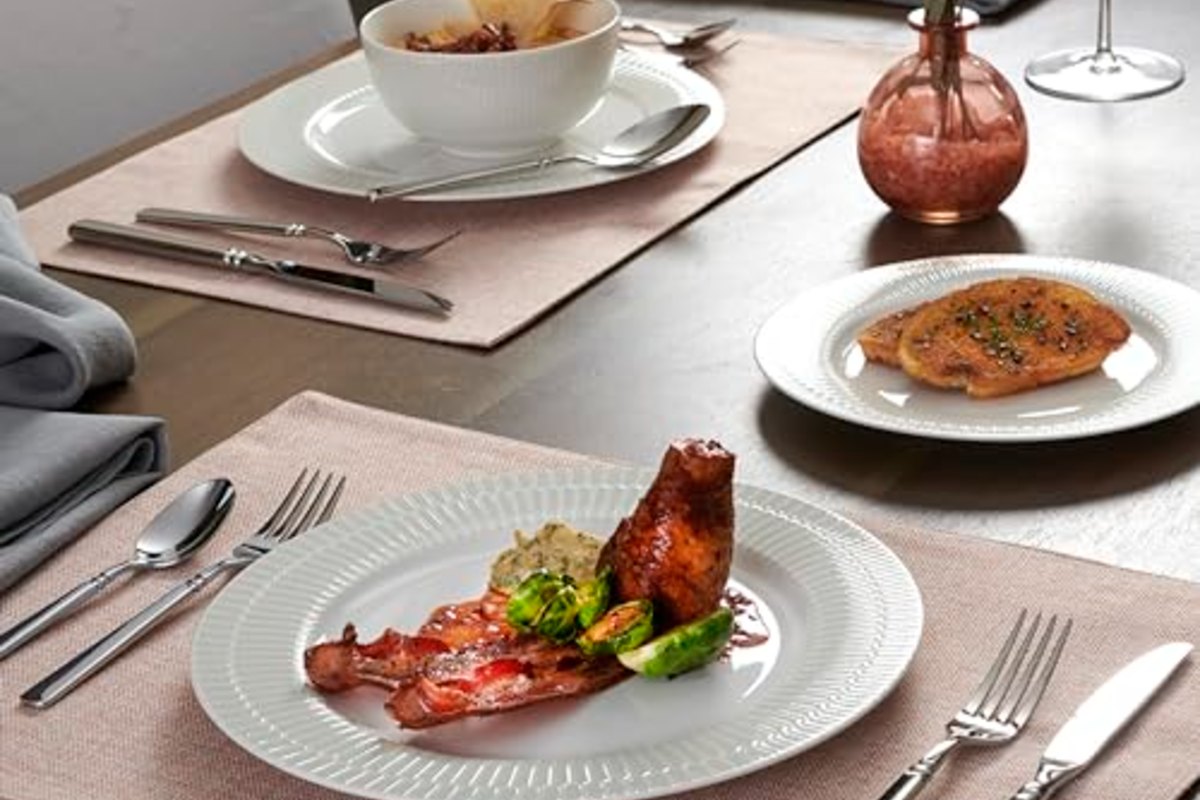 A dinner table mid-meal, plates served and flatware set on either side