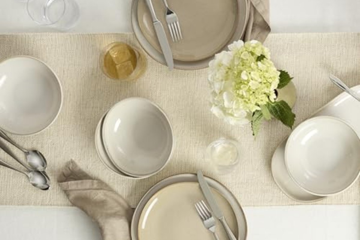 A neutral table seen from above, two settings of plates and bowls on a linen runner