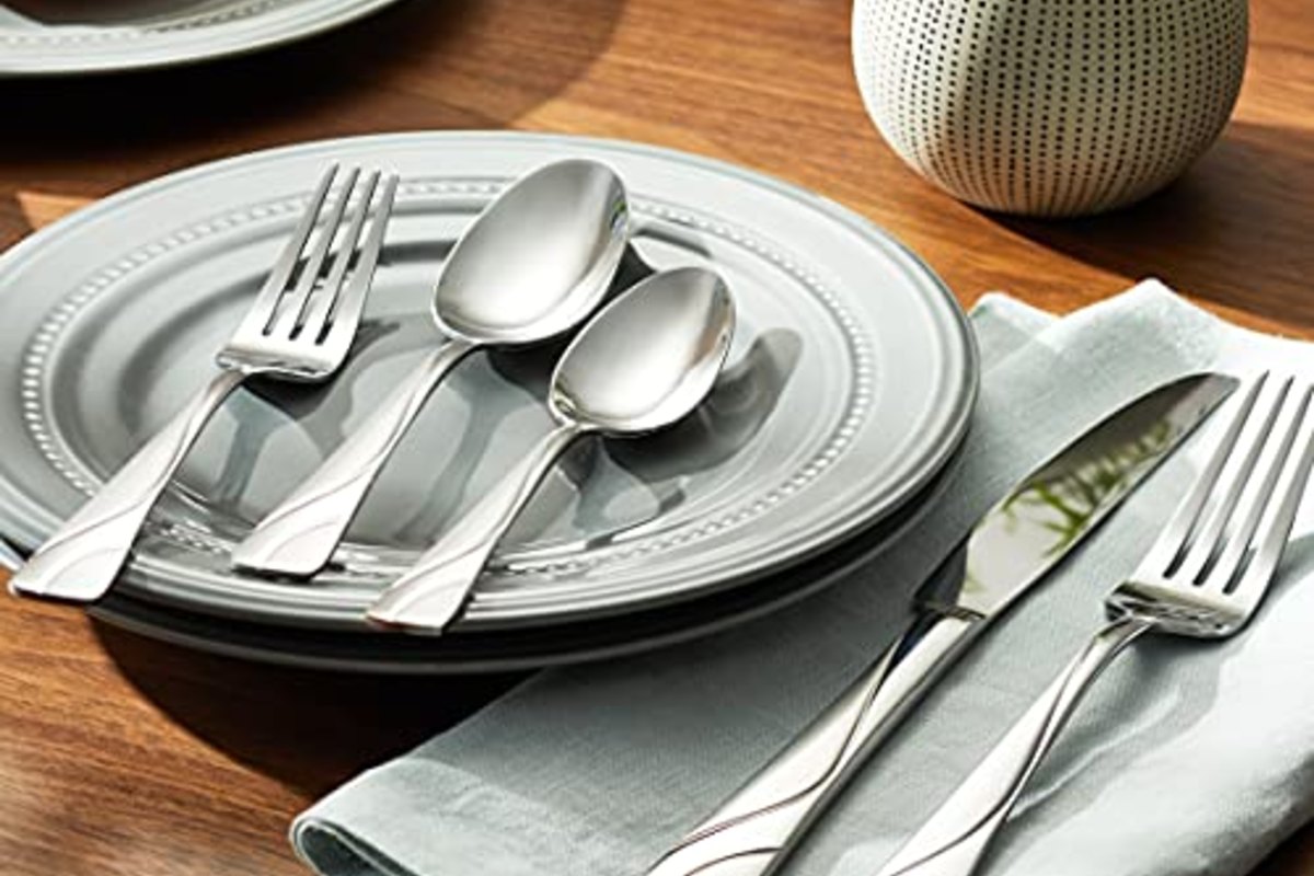 Two settings on pale sage linen with stacked plates and a small vase between them